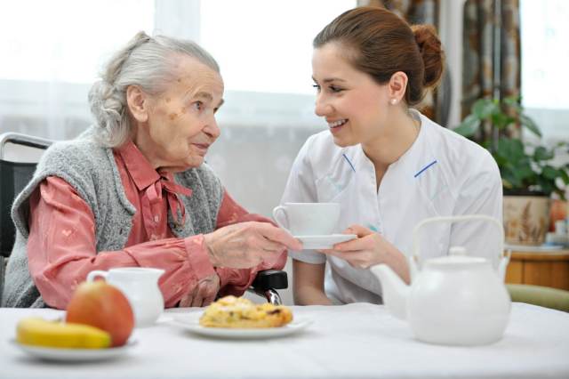 Senior woman eats lunch at retirement home